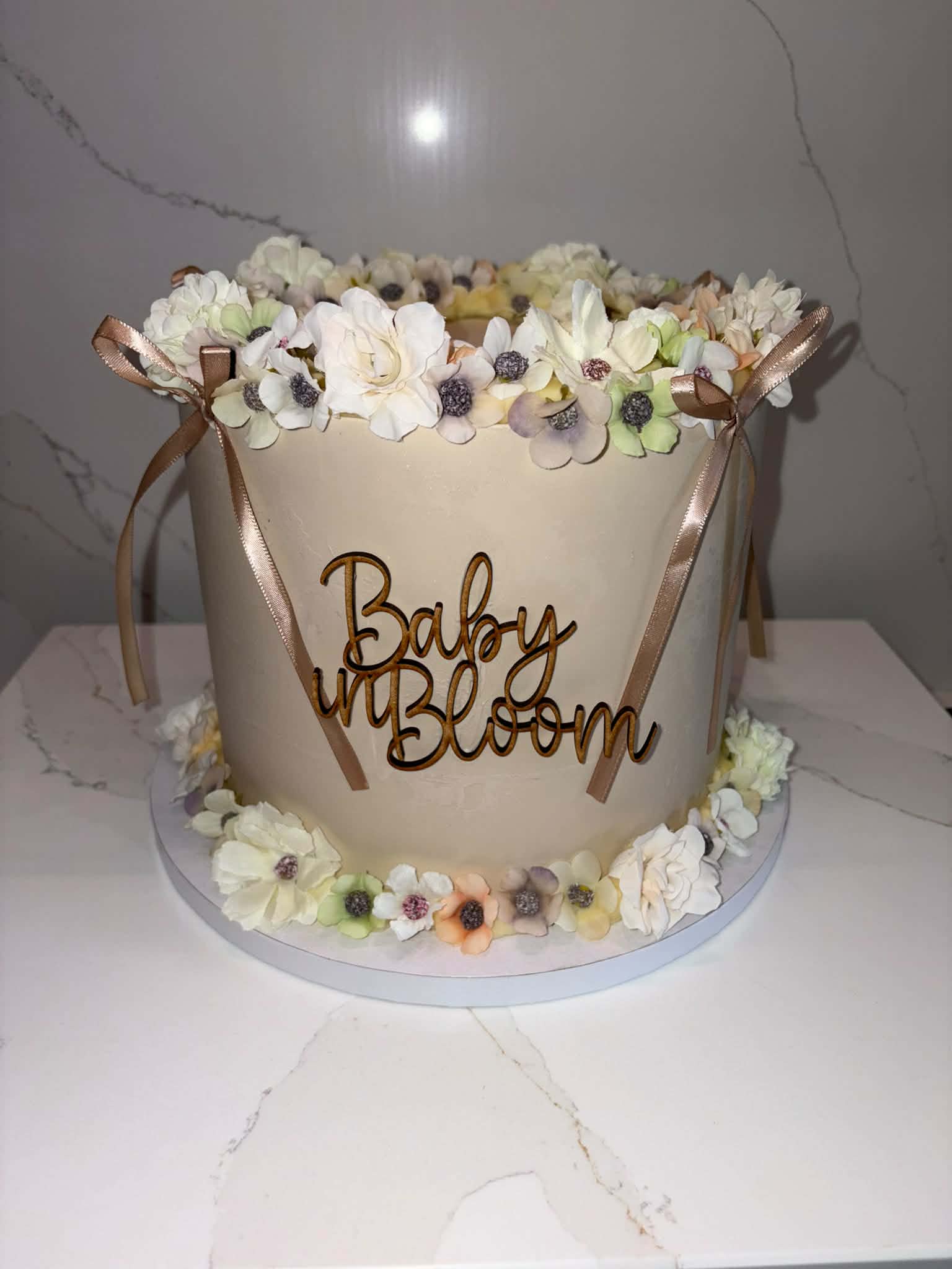 'Baby in Bloom' baby shower cake with a champagne buttercream finish, dried florals and ribbon
